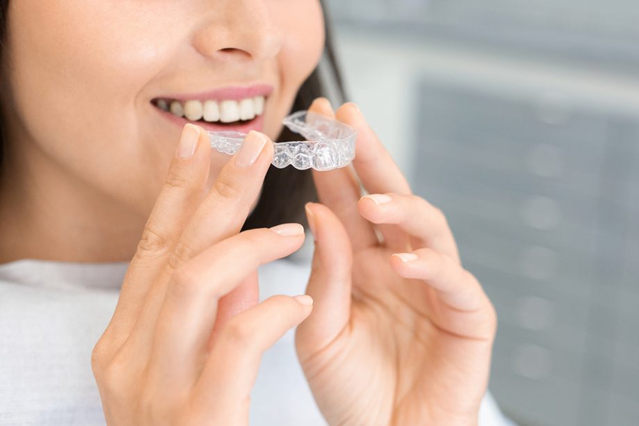 a woman holding Invisalign clear aligners