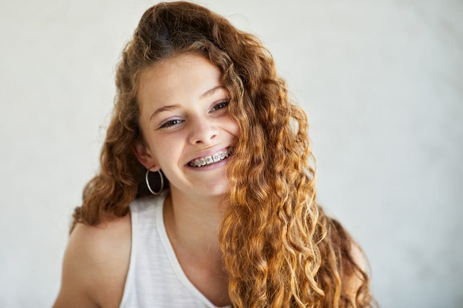 a girl smiling with traditional braces