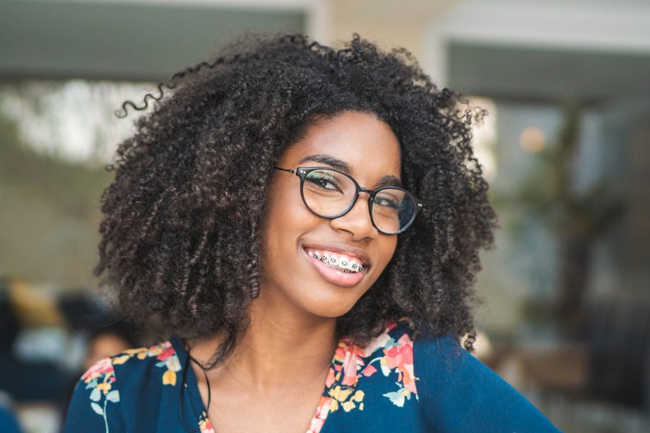 a teenager smiling with glasses and braces on her teeth